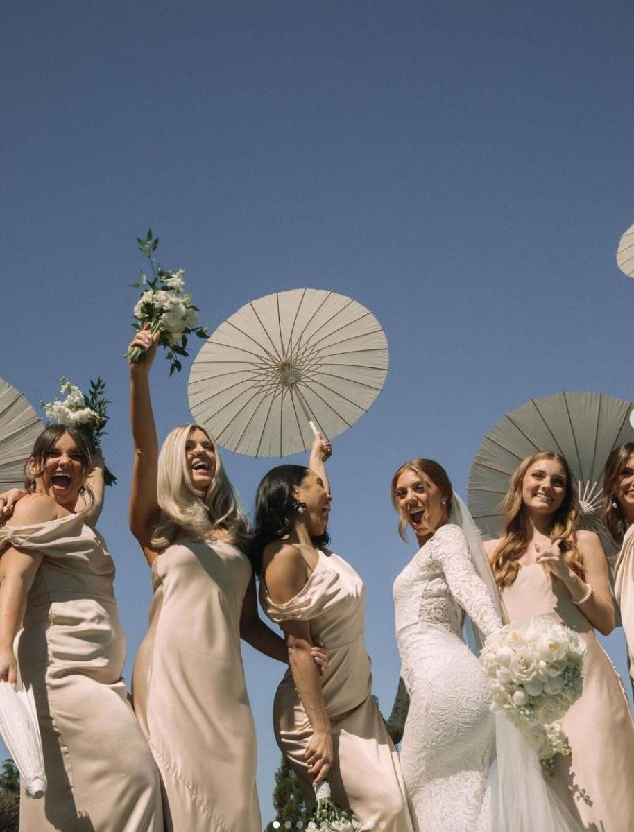 Mariée et ses demoiselles d'honneur avec des ombrelles blanches 